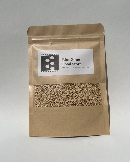 Unhulled Sesame Seeds in a kraft stand-up pouch with a clear window, Blue Zone Food Store label, on a light grey studio background
